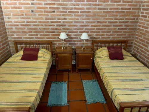 two beds in a room with a brick wall at Pintoresca casa con pileta in Yala