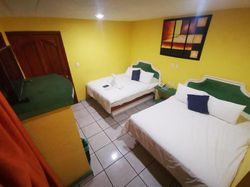 a hotel room with two beds and a chair at Casa Real in Poza Rica de Hidalgo