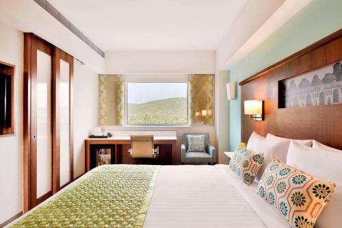 a hotel room with a bed with a desk and a window at Fairfield by Marriott Belagavi in Belgaum