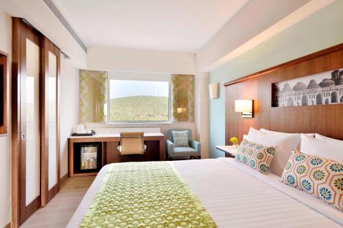 a hotel room with a bed and a desk and a window at Fairfield by Marriott Belagavi in Belgaum