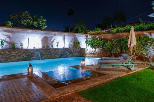 a swimming pool with a chair and an umbrella at Villa Taj Sofia & Spa in Marrakech