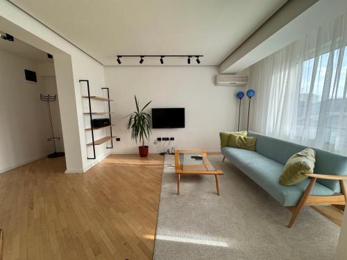 un salon avec un canapé bleu et une télévision dans l'établissement - SERENITY Apartment -, à Skopje