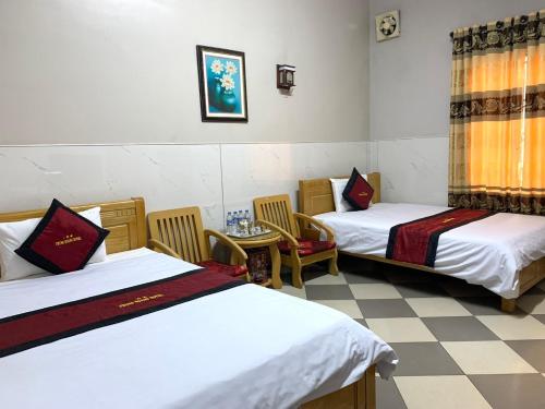 Cette chambre comprend deux lits, une table et des chaises. dans l'établissement KHÁCH SẠN PHỤNG HOÀNG, à Quang Tri