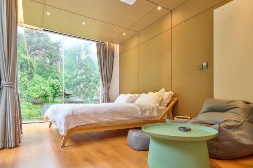 a bedroom with a bed and a chair and a window at Zhumaxi Leisure Lodge in Zhangjiajie