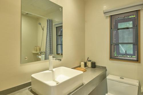 a white bathroom with a sink and a mirror at Zhumaxi Leisure Lodge in Zhangjiajie