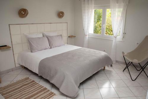 a white bedroom with a large bed and a window at Domaine des demoiselles - Chambres d'hôtes in Hauteville