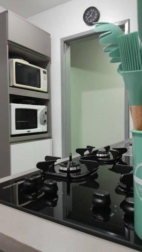 a kitchen with a stove and a microwave at Apartamento há 5 min do Centro de Criciúma. in Criciúma