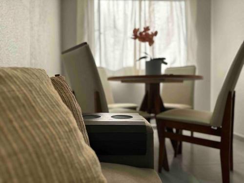 a living room with a table and a chair with a suitcase at Apartamento há 5 min do Centro de Criciúma. in Criciúma