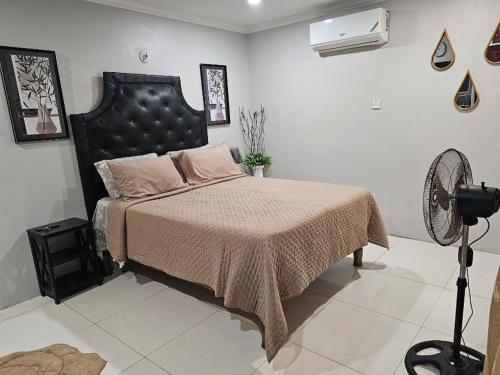 オーチョ・リオスにあるSecret Hideawayのベッドルーム1室(黒いヘッドボード付きのベッド1台、ファン付)