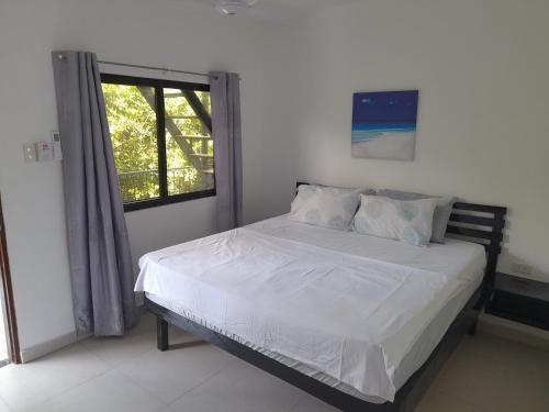 a bedroom with a bed with white sheets and a window at Bohol Jewel Resort in Dauis