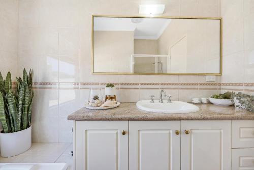 a bathroom with a sink and a mirror at Your Sunny Pool & Ocean Escape in Coogee