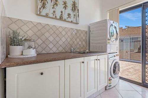 a kitchen with a sink and a washing machine at Your Sunny Pool & Ocean Escape in Coogee