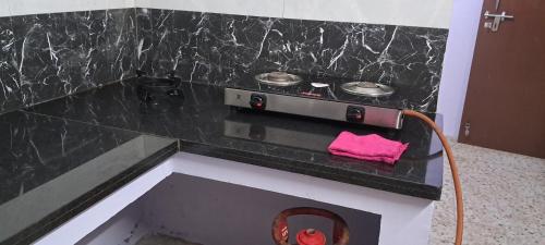 una cucina con piano cottura e piano cottura di lavoro nero. di Major Madi Residency a Pondicherry