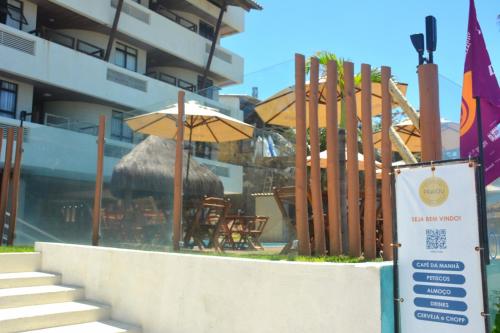 a restaurant with chairs and umbrellas in front of a building at Apto Romântico frente mar vista mar Elegance Flat in Natal