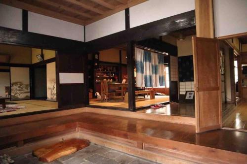 una sala de estar con suelo de madera y una habitación con mesa en Private stay 120years old Japanese-style house, en Okinoshima