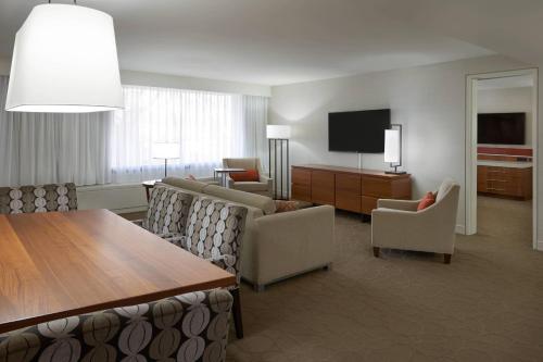 a living room with chairs and a table and a television at Delta Hotels by Marriott Toronto Airport & Conference Centre in Toronto