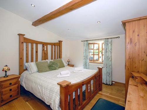 a bedroom with a large bed with a wooden headboard at Yr Hen Glowty in Little Newcastle
