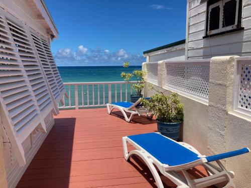 a balcony with two lounge chairs and the ocean at Villa Jarrow in Christ Church