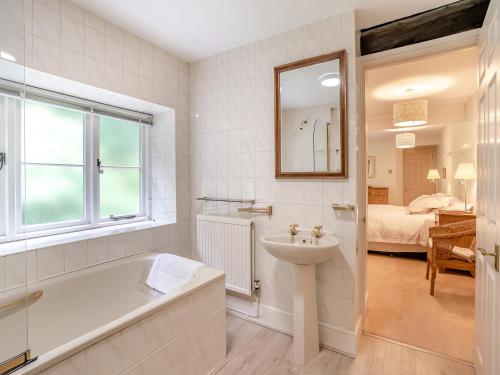 a bathroom with a bath tub and a sink and a mirror at The Carriage House in Llanwenarth