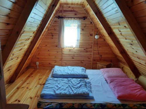a bed in a log cabin with a window at A comfortable house with a private garden, Rusinowo in Rusinowo