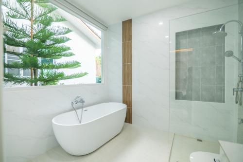 a white bathroom with a tub and a shower at In Love Chiangmai หลงรักเชียงใหม่ in Ban Tai