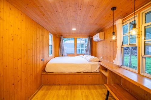 a bedroom with a bed in a wooden room with windows at In Love Chiangmai หลงรักเชียงใหม่ in Ban Tai
