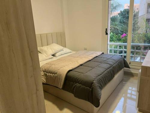 a bed in a bedroom with a large window at High quality apartment Madinty in Cairo