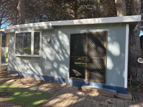 a tiny house sitting next to a tree at Second Valley Caravan Park in Second Valley