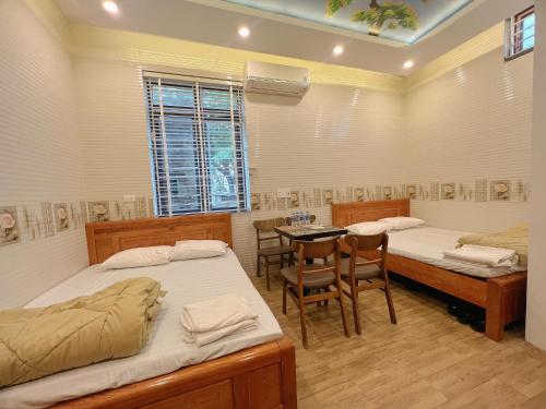 a room with two beds and a table and chairs at The Mountain View Homestay in Ninh Binh