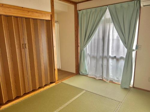 an empty room with a large window and a door at Onna yuntaku-SEVEN Hotels and Resorts- in Onna