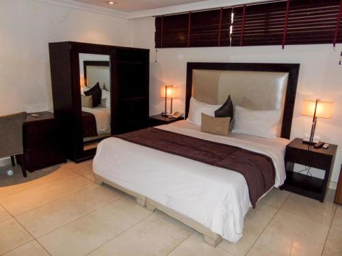 1 dormitorio con 1 cama grande y espejo grande en S & S Hotel & Suites en Lagos