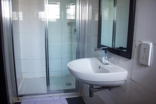 uma casa de banho branca com um lavatório e um chuveiro em S & S Hotel & Suites em Lagos