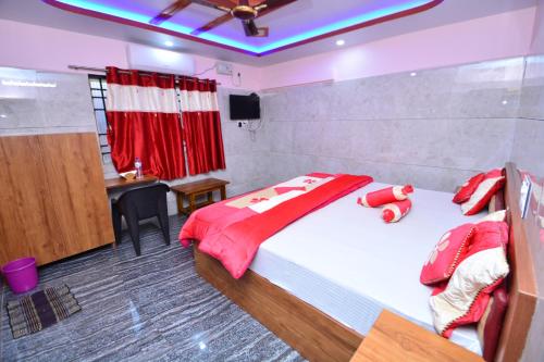 a bedroom with a large bed with red sheets and a table at Aryan residency in Māvalli