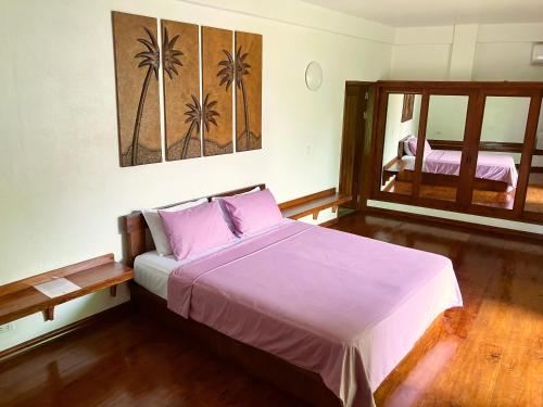 a bedroom with a bed with purple sheets and a window at Villa Formosa Panglao in Panglao