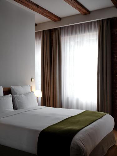 a bedroom with a large bed with a window at 5 Terres Hotel & Spa - MGallery Collection in Barr
