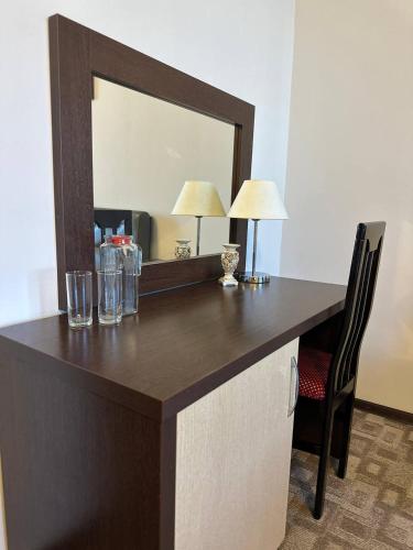 a desk with two glasses and a mirror at Tanzharyk Hotel in Aktobe