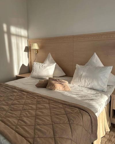 a large bed with white pillows and a headboard at Tanzharyk Hotel in Aktobe