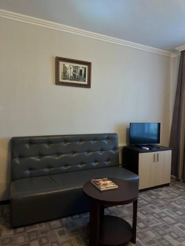 a living room with a couch and a table at Tanzharyk Hotel in Aktobe