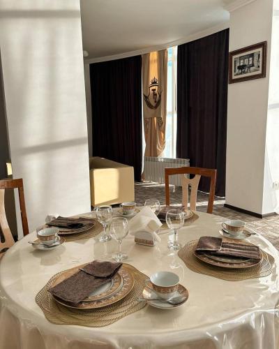 a table with plates and wine glasses on it at Tanzharyk Hotel in Aktobe