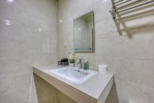 a white bathroom with a sink and a mirror at RR Cottage in Nusa Penida