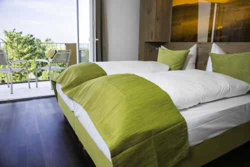 a green and white bed in a room with a balcony at Hotel Rheingold in Gailingen