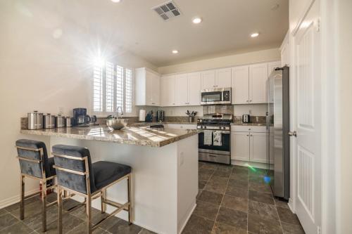 a kitchen with white cabinets and a counter with two chairs at Peaceful 4BR Home With Mountain View in Ormand