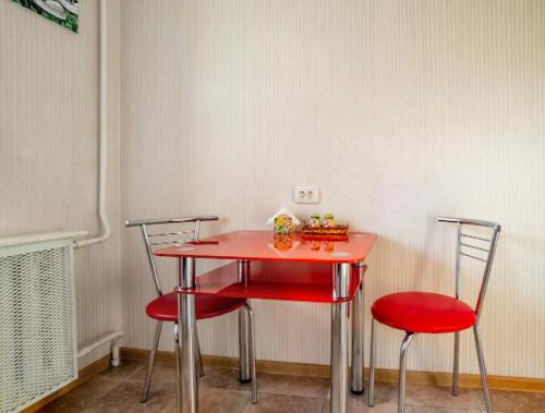 a red table and two chairs in a room at Apartment with a panoramic view of Podil near the metro in Kyiv