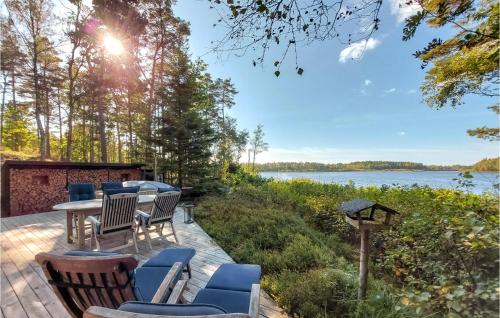 a deck with chairs and a table with a view of a lake at Stunning Home In Skånes Fagerhult in Skånes Fagerhult
