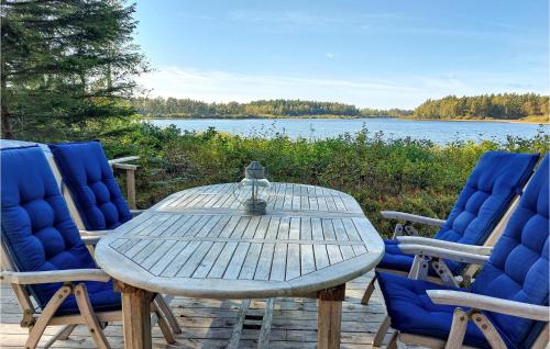 a wooden table and chairs with a view of a lake at Stunning Home In Skånes Fagerhult in Skånes Fagerhult