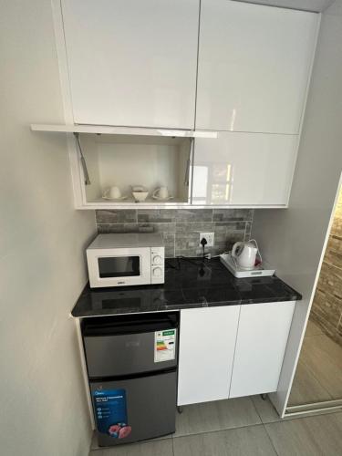 a kitchen with white cabinets and a microwave at 5 on Crossways in East London
