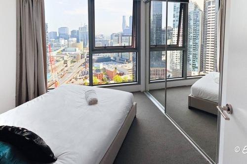 ein Hotelzimmer mit einem Bett und einem großen Fenster in der Unterkunft Southbank 26F 1BR Sea-View City Skyline Pool & Gym in Melbourne