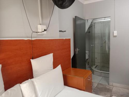 een slaapkamer met een bed en een glazen douche bij Silent Night Guest House Sunnyside Pretoria in Pretoria