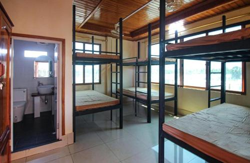 a room with four bunk beds and a bathroom at The Pig Pen Hostel & BBQ in Kampot