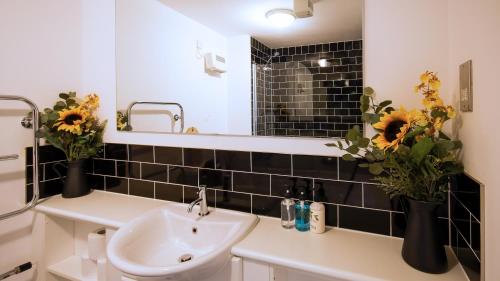 a bathroom with a sink and a mirror and flowers at SOUTHAMPTON Central Apartments - Wise Stays in Southampton